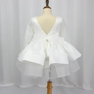 Detail of white girls' dress with sequins, V-back zipper, and large waist bow decoration