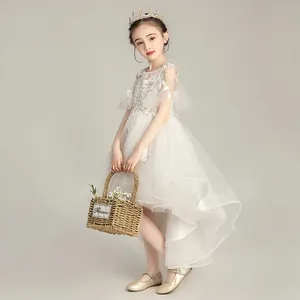 Detalle del vestido de niña blanco con tul asimétrico y aplicaciones florales de encaje