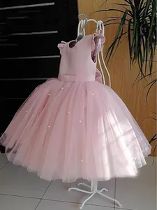 Pink sleeveless tiered tulle flower girl dress with pearls on white mannequin stand