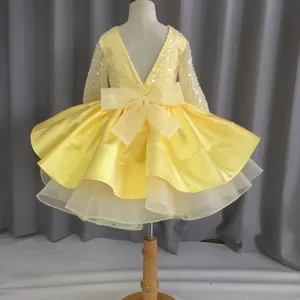 Detail of yellow girls dress featuring a large bow and sequined lace back design