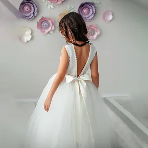 Elegant sleeveless white girls ball gown with V-back detail and large satin bow decoration