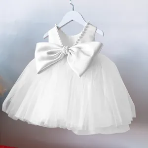 Close-up of white flower girl dress featuring pearl neckline and large satin bow detail