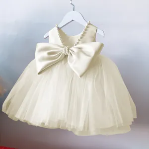 Close-up of champagne flower girl dress with pearl neckline and large satin back bow