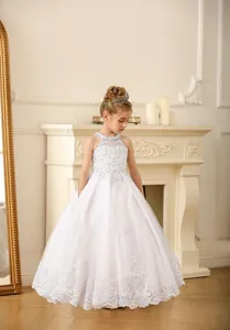 Detail of white lace flower girl dress featuring intricate embroidery and halter neckline