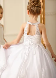Detail of elegant white lace girls dress featuring a backless halter neck and mesh tutu skirt