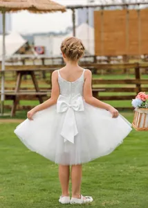 Dettaglio posteriore dell'abito bianco in pizzo per bambina con grande fiocco e tulle