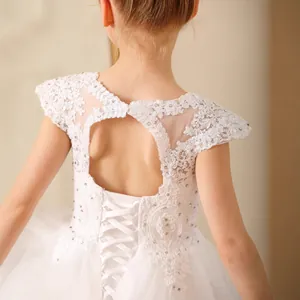 Detail of white flower girl dress featuring lace embroidery and back ribbon lacing design