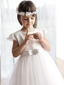Robe blanche en dentelle pour demoiselle d'honneur avec ceinture rose et broche bijoux