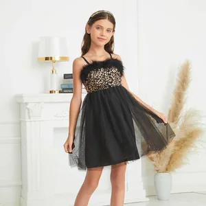 Detail of girls' black tulle party dress with gold sequins and feather trim on the bodice