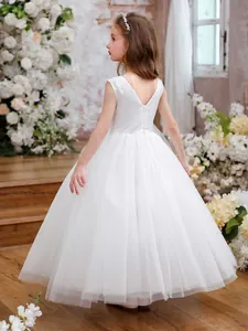 Detail of elegant white flower girl dress featuring backless V-neck and layered tulle skirt