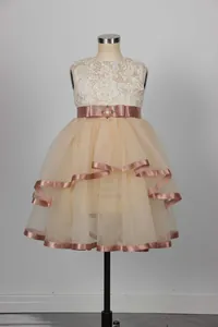 Detail of flower girl dress with lace bodice, champagne ribbon, and tiered tulle skirt