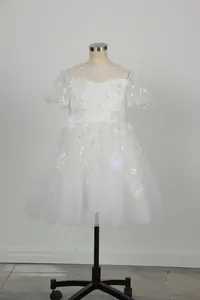 Details des weißen Blumenmädchenkleids mit aufwendiger Stickerei und Puffärmeln