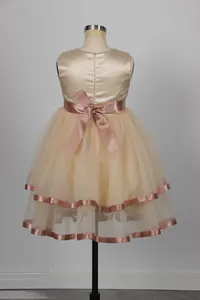Detail of champagne satin back with large bow and multi-layered tulle hem on princess gown