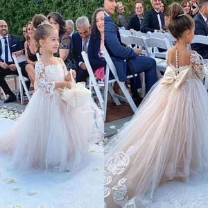 Detalle de vestido de damita de honor con encaje, mangas largas y lazo en la espalda
