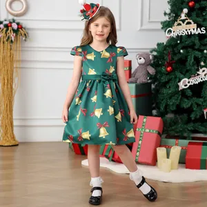 Detailed close-up of green satin girls' Christmas dress with gold bell and red bow patterns