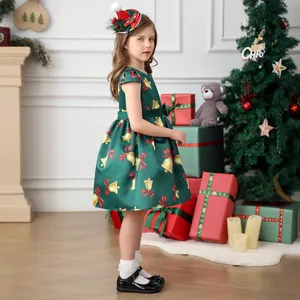 Detail of girls' green satin Christmas dress with gold bell prints and red bow accents