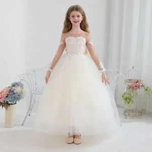 Detalle de vestido de tul color marfil para niña con encaje y mangas largas transparentes
