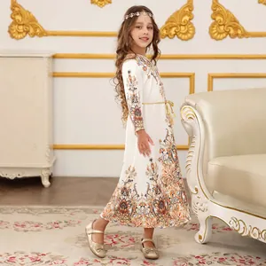 Dettaglio dell'abito etnico bianco da bambina con stampe vintage e cintura dorata