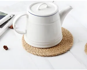 Gros plan d'une théière en céramique blanche sur un set de table épais en jute tressé