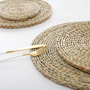 Detailed view of hand-woven straw round placemats with natural grass texture and cutlery