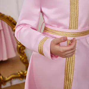 Detail of pink satin girl's dress with intricate gold lace trim and woven patterns