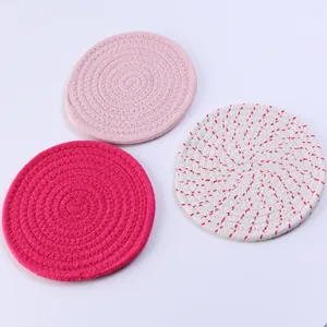 Vista detallada de tres posavasos de algodón trenzado en rosa y blanco con textura redonda