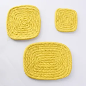 Dettaglio di sottobicchieri in cotone intrecciato giallo brillante in forme quadrate e ovali
