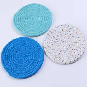 Detalle de tres posavasos de algodón trenzado en colores menta, azul y crema natural