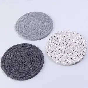 Detalle de tres posavasos redondos de algodón trenzado en color gris y beige
