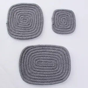 Dettaglio di tre sottobicchieri in cotone intrecciato grigio resistenti al calore su bianco