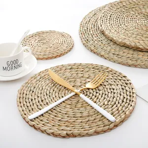 Japanese style hand-woven round straw placemats with cutlery on white background