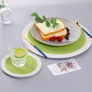 Detailed top view of a green and white cotton woven placemat set on a grey table