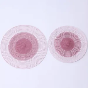 Top view of two round gradient pink ramie placemats with woven spiral texture for heat insulation