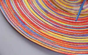 Close-up of colorful round woven placemat with vibrant concentric circular spiral patterns