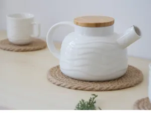 Détail de la théière en céramique blanche texturée avec dessous de plat en jute tressé