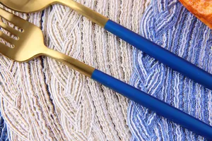 Close-up of matte gold and navy blue cutlery on a textured round woven placemat