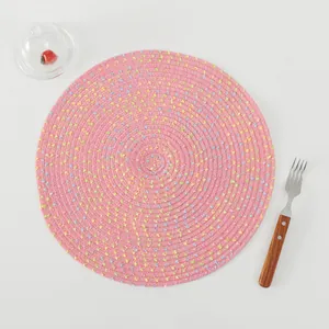 Detailed top view of pink woven placemat with colorful threads on minimalist table