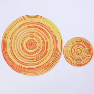 Macro detail of round woven placemats in vibrant yellow and orange spiral patterns