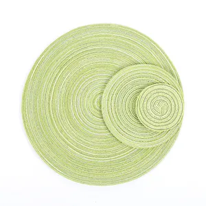 Detailed top view of three various sized woven heat resistant placemats in green and white