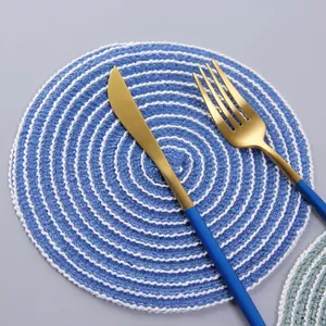Blue and white spiral woven ramie placemat with stainless steel cutlery on grey background