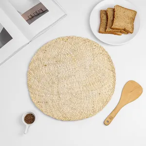 Close-up of hand-woven round seagrass placemat with spiral texture on white table