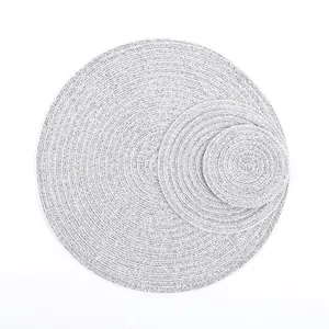 Detail view of woven grey and white heat-resistant round placemats in three varied sizes