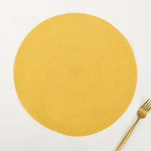 Top view of yellow round ramie placemat with spiral woven texture and gold fork