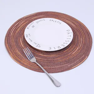 Close-up of circular ramie woven placemat with gradient brown spiral texture and ceramic plate