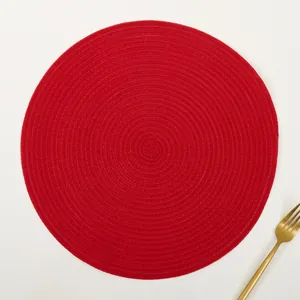 Macro detail of red round woven placemat with golden fork on minimalist background