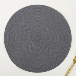 Close-up of circular hand-woven charcoal grey ramie placemat with elegant gold fork detail