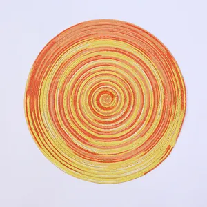 Macro detail of round woven ramie coaster with orange and yellow spiral texture