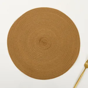 Close-up of brown round ramie placemat with detailed spiral woven texture and a gold fork