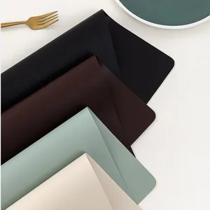 Detail of stacked waterproof PU leather placemats in black brown green and beige colors