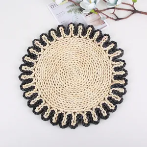 Close-up of a round corn husk placemat with spiral weave and black scalloped edges